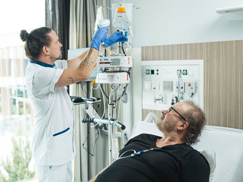 Verpleegkundige verzorgt patiënt in bed