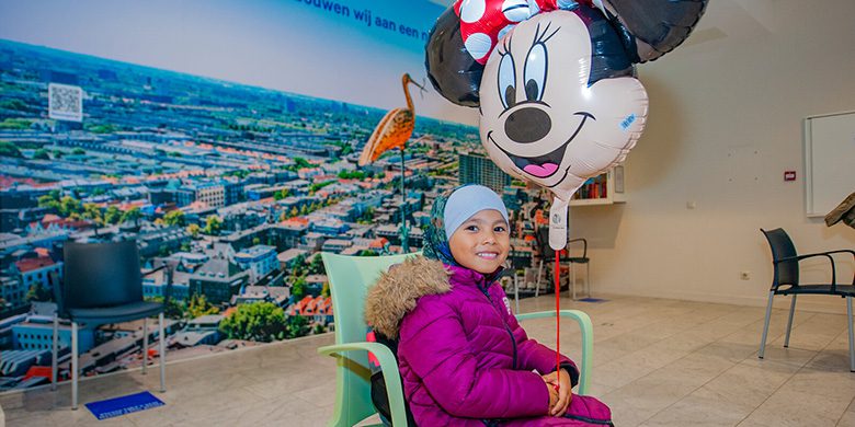 Meisje gaat met Minnie Mouse ballon bij iemand op bezoek